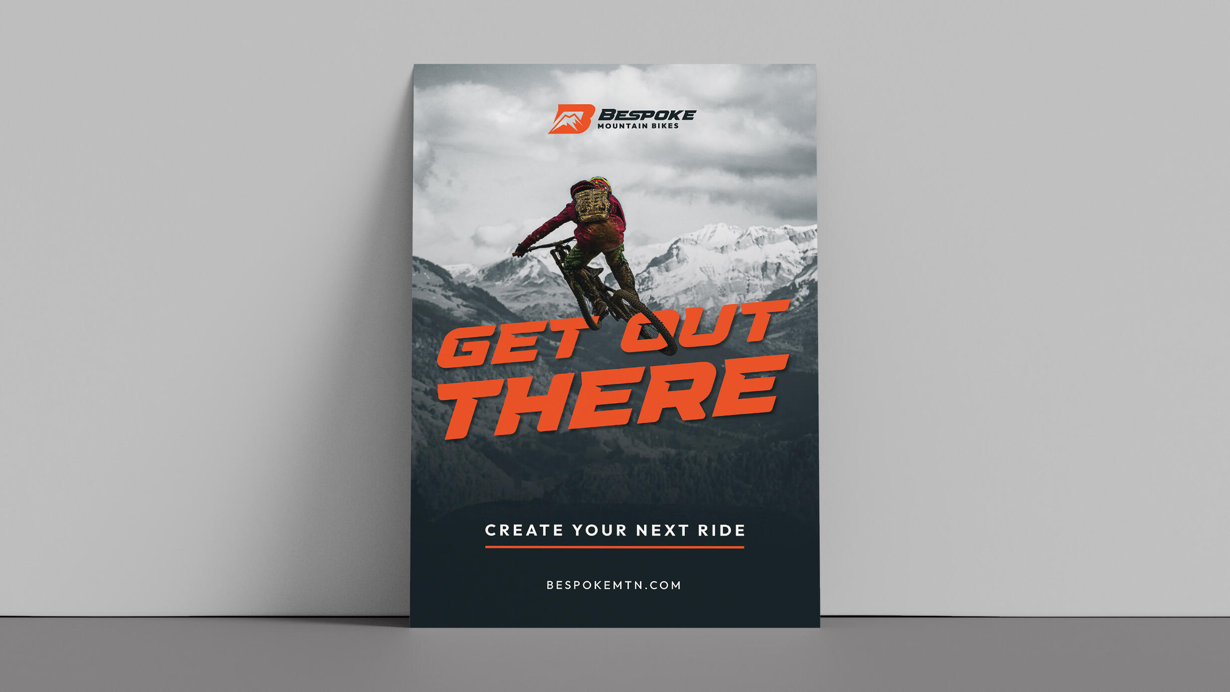 An advertisement for Bespoke Mountain Bikes featuring text that says, “Get Out There. Create Your Next Ride.” Features a mountain biker jumping in the air.